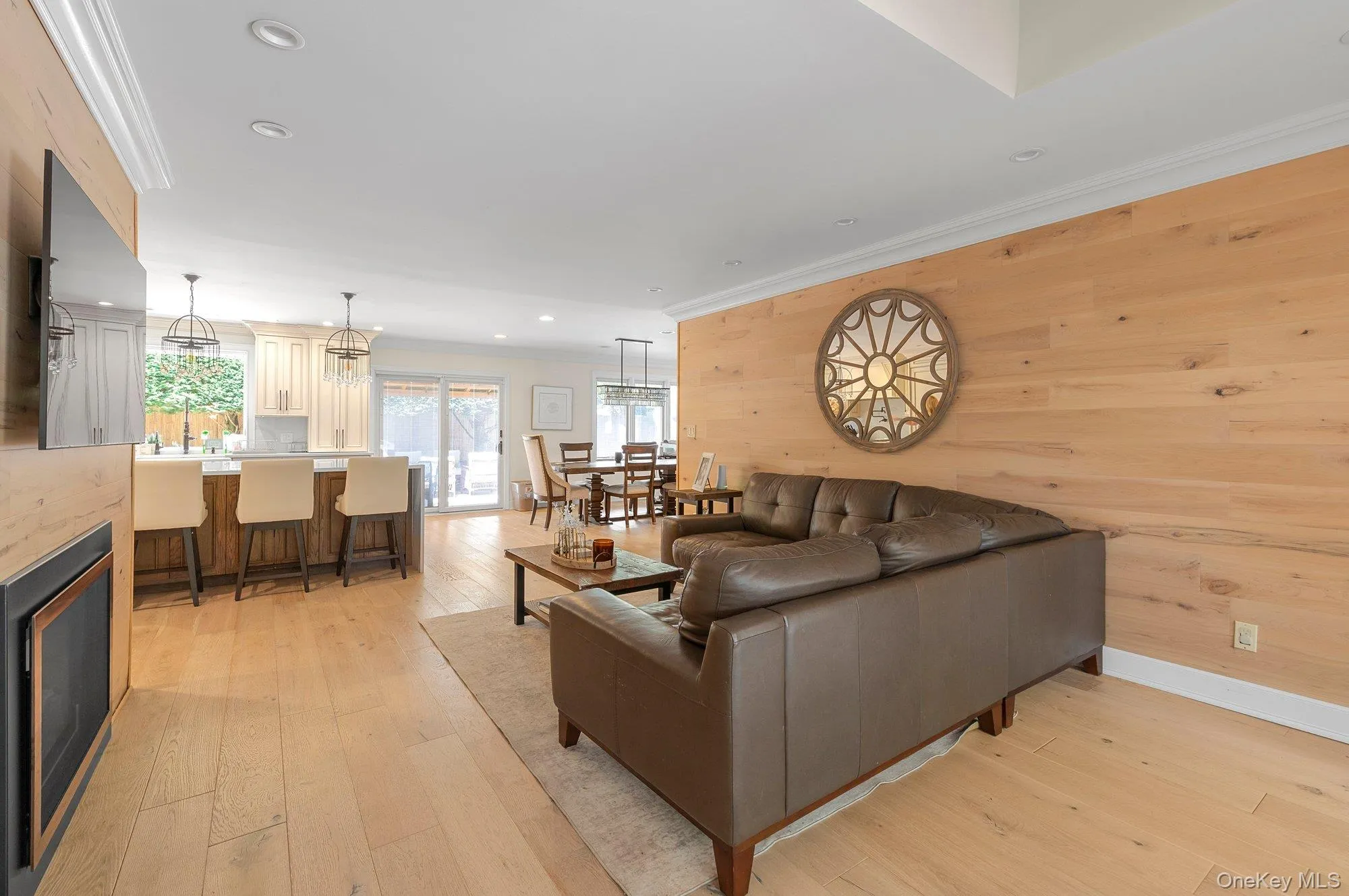 Open-concept living space with light wood-finish flooring, recessed lighting, and crown molding Open-concept living space with light wood-finish flooring, recessed lighting, and crown molding