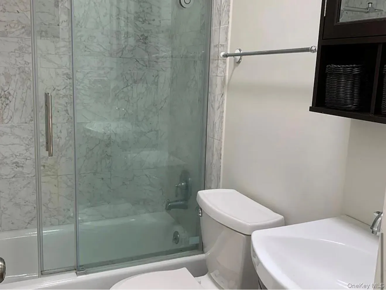Full bathroom featuring toilet, shower / bath combination with glass door, and a sink Full bathroom featuring toilet, shower / bath combination with glass door, and a sink