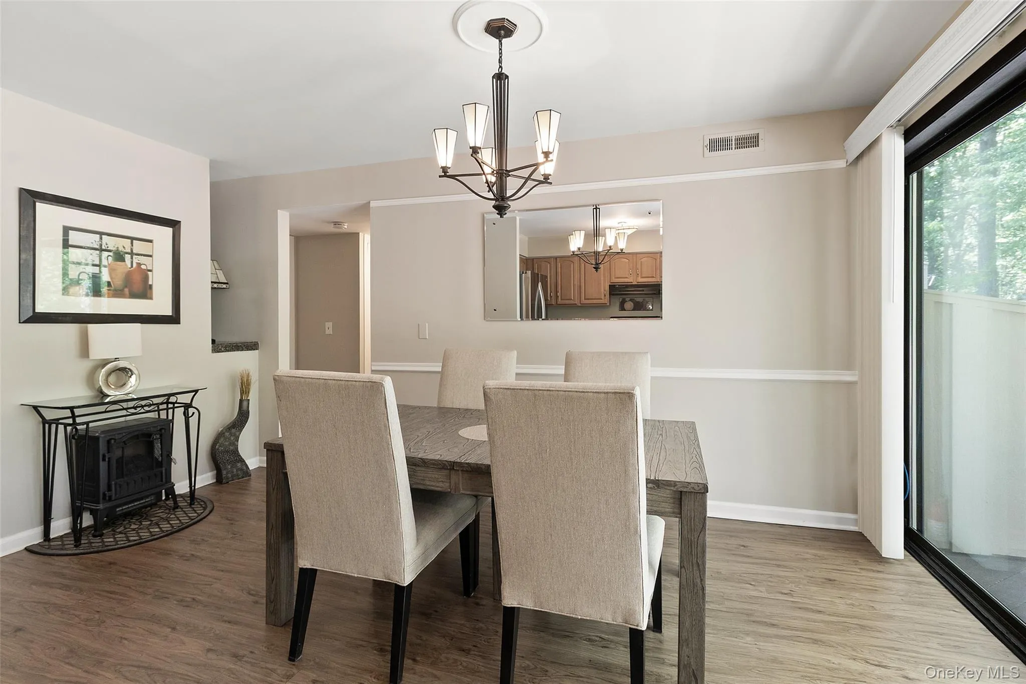 Dining area featuring wood-finish flooring, a chandelier with a ceiling medallion, chair rail molding, and a sliding glass door Dining area featuring wood-finish flooring, a chandelier with a ceiling medallion, chair rail molding, and a sliding glass door