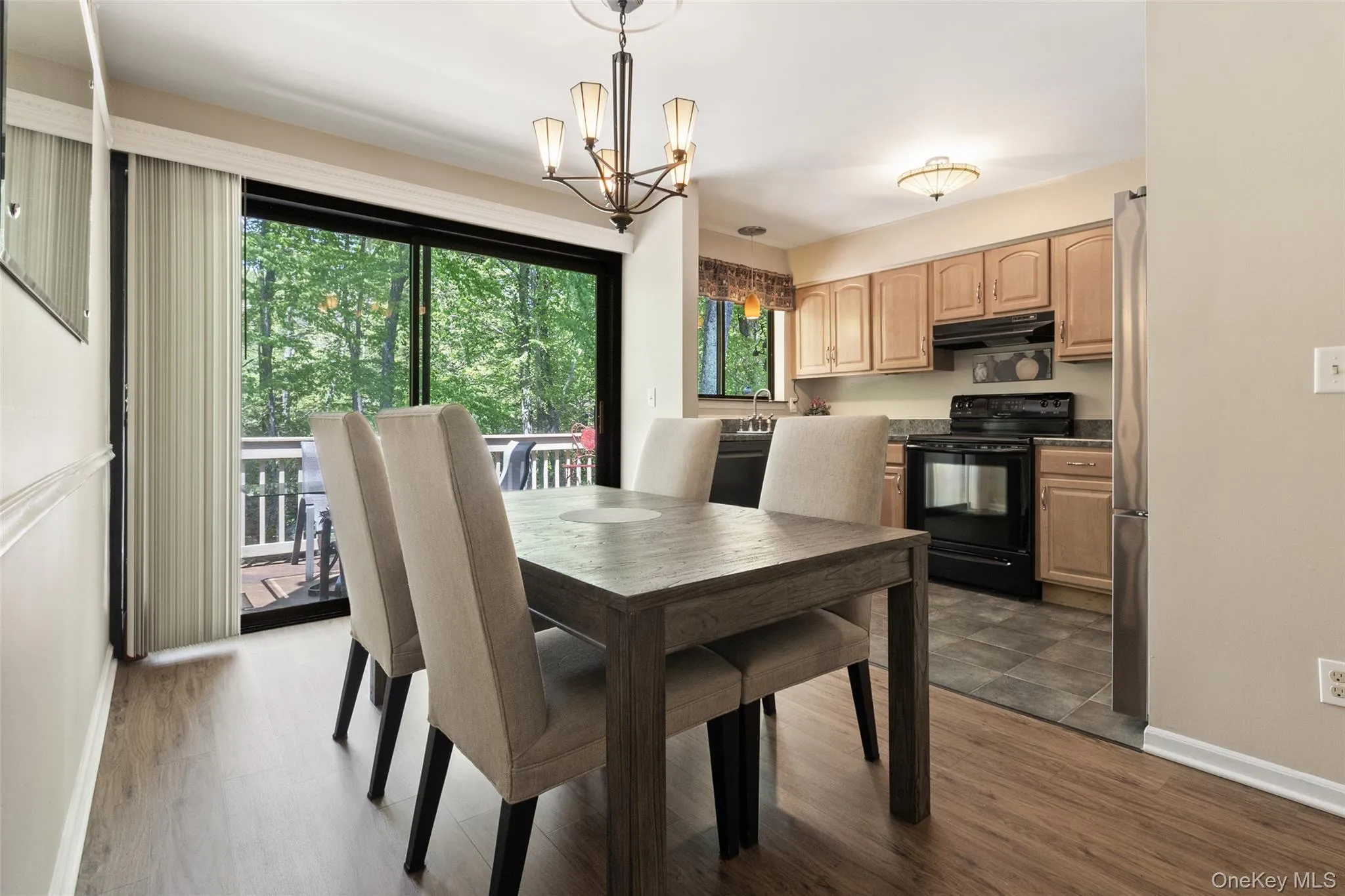 Dining area featuring wood-finish flooring and a contemporary chandelier and a sliding glass door Dining area featuring wood-finish flooring and a contemporary chandelier and a sliding glass door