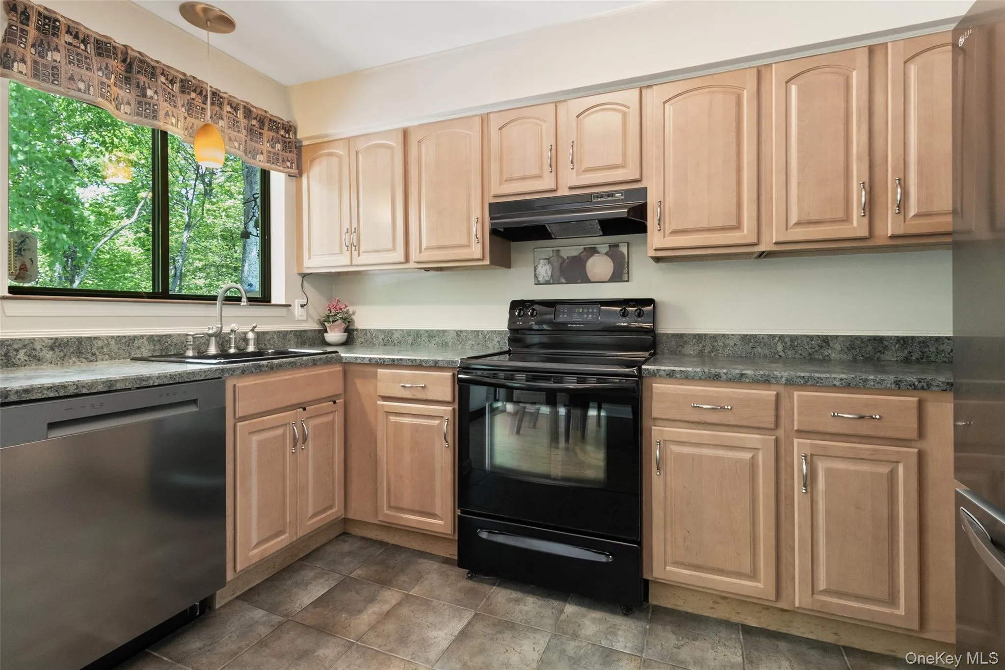 Kitchen featuring light wood-finish cabinetry, beveled countertop, and stainless steel dishwasher and refrigerator Kitchen featuring light wood-finish cabinetry, beveled countertop, and stainless steel dishwasher and refrigerator