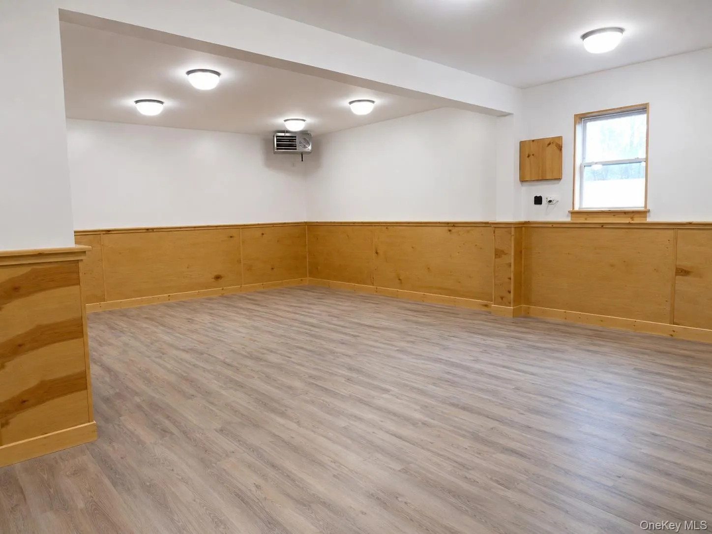 Spacious room with light wood-finish flooring and light wood wainscoting Spacious room with light wood-finish flooring and light wood wainscoting