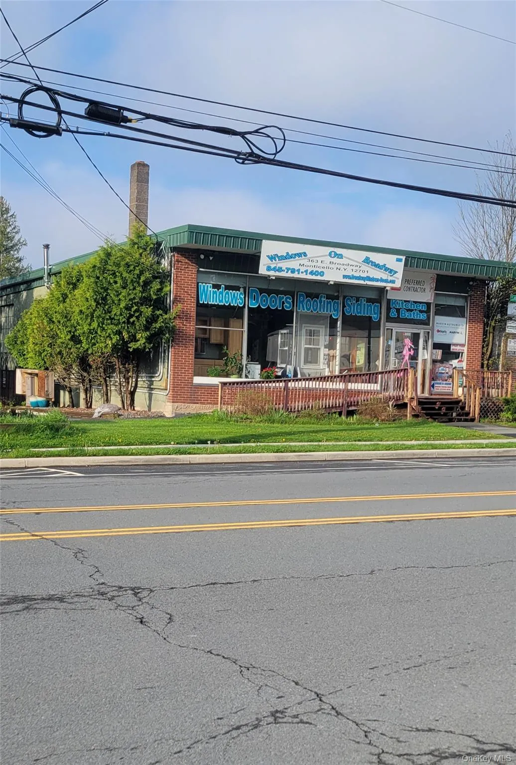 Front of the Commercial building featuring a brick facade, large display windows, and a green awning Front of the Commercial building featuring a brick facade, large display windows, and a green awning