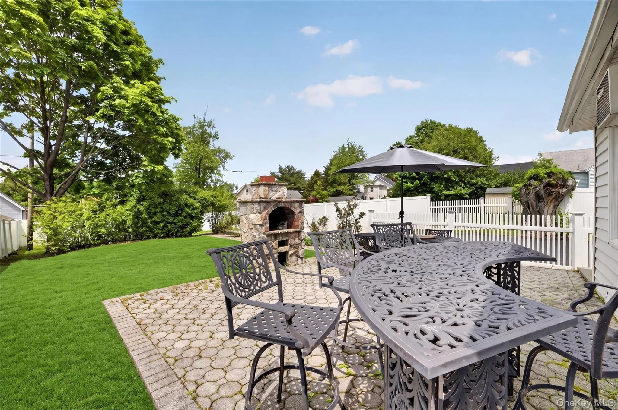 Expansive paver patio featuring a built-in stone oven and a dedicated pathway Expansive paver patio featuring a built-in stone oven and a dedicated pathway