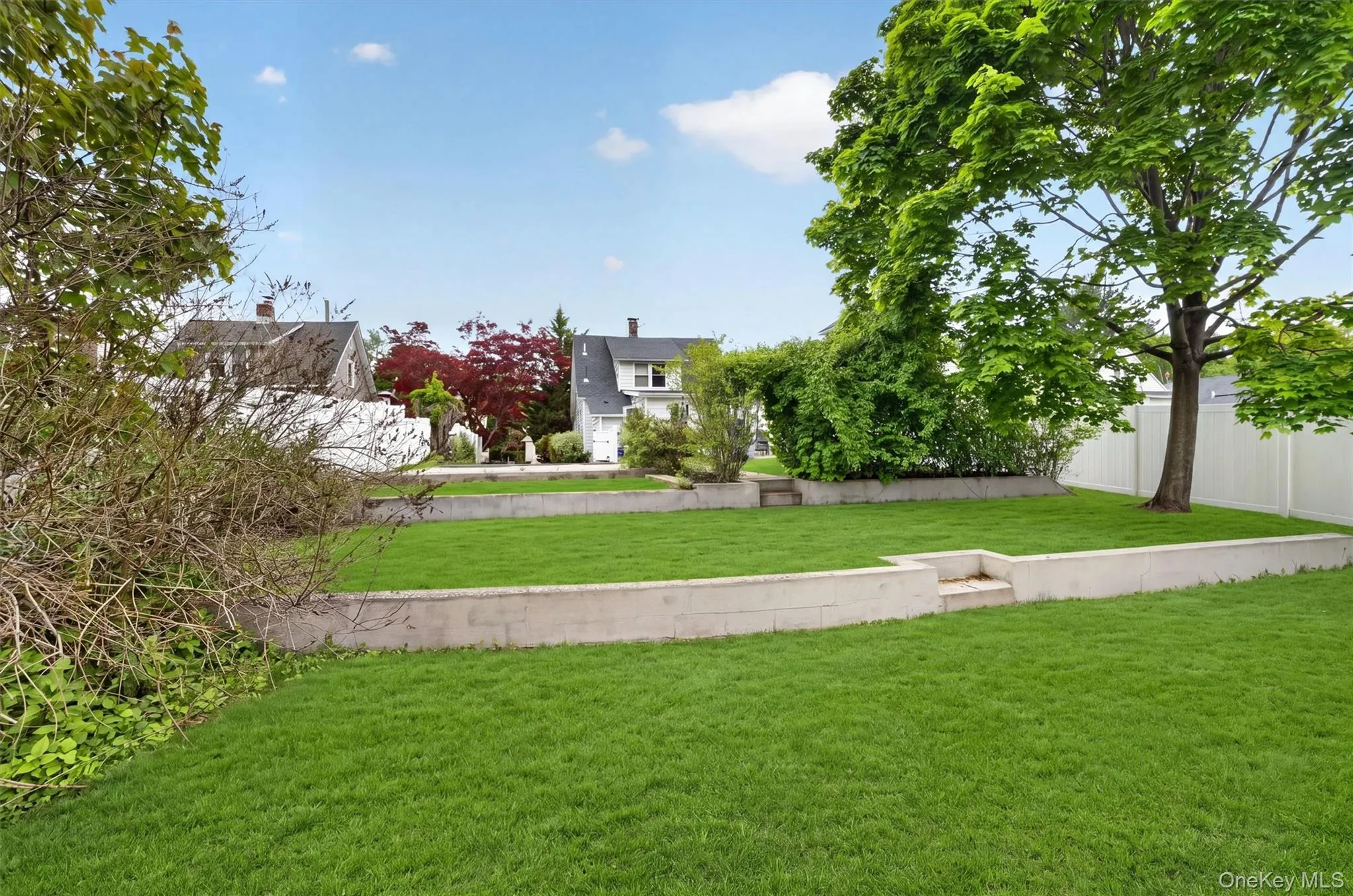 Expansive lawn area featuring a tiered design with concrete retaining walls. Expansive lawn area featuring a tiered design with concrete retaining walls.