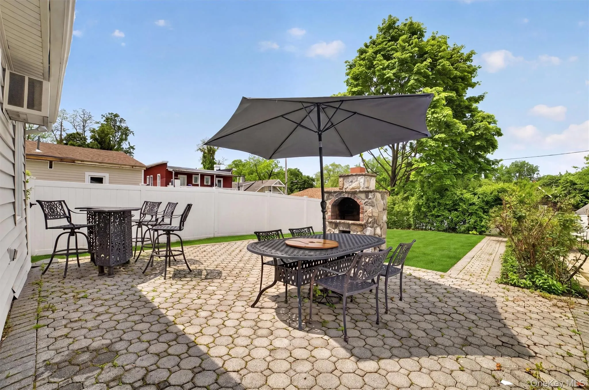 Expansive paver patio featuring a built-in stone oven and a dedicated pathway Expansive paver patio featuring a built-in stone oven and a dedicated pathway