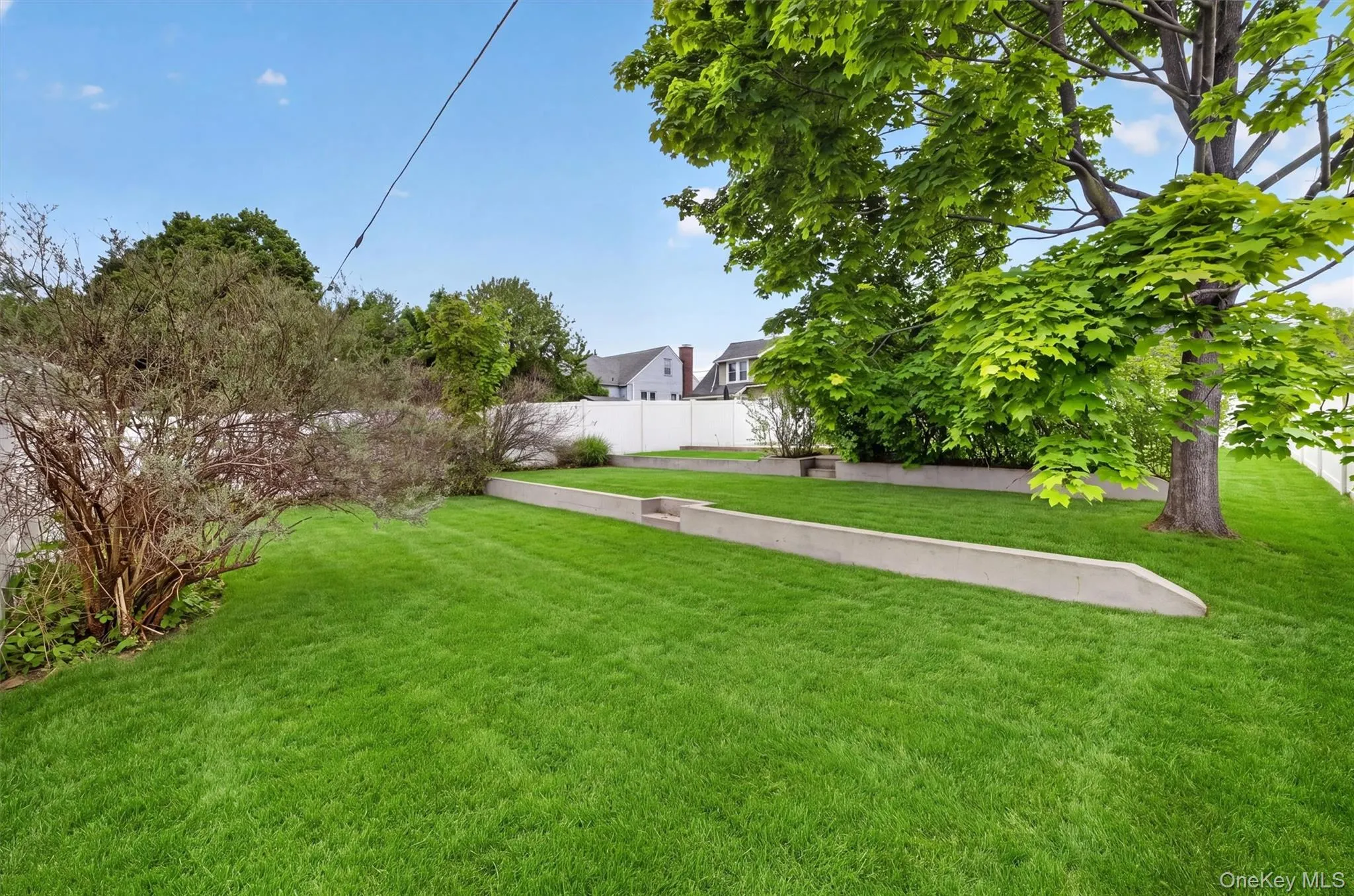 Expansive lawn area featuring a tiered design with concrete retaining walls. Expansive lawn area featuring a tiered design with concrete retaining walls.