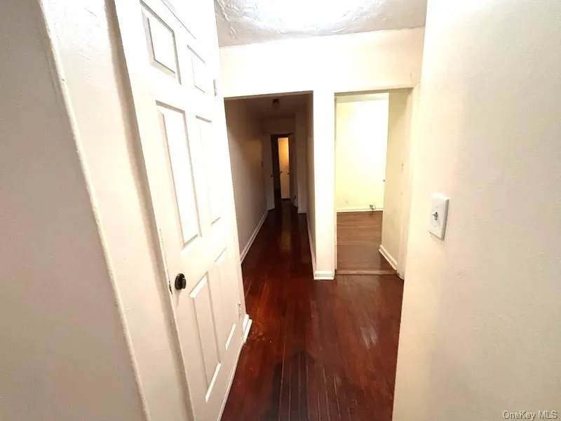 Corridor featuring dark wood-type flooring and baseboards Corridor featuring dark wood-type flooring and baseboards