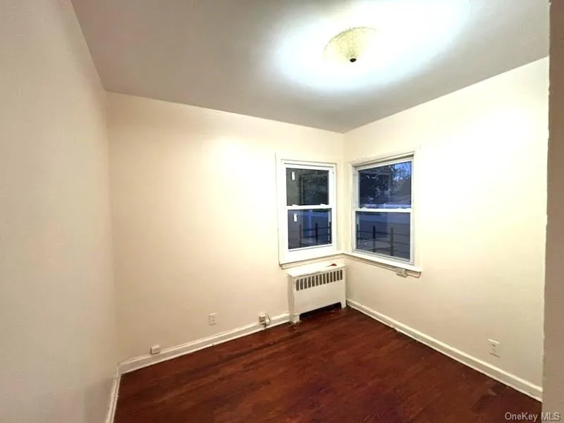 Empty room featuring radiator and dark wood-style floors Empty room featuring radiator and dark wood-style floors