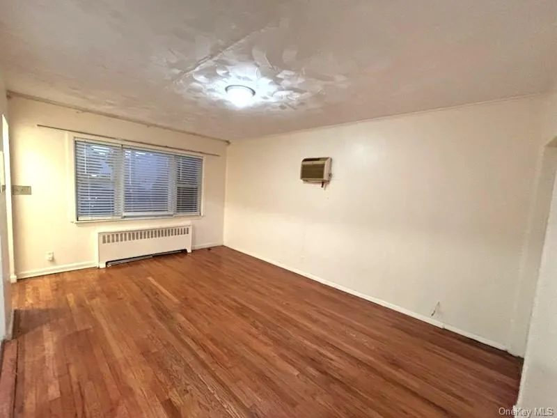 Spare room featuring radiator heating unit and dark wood finished floors Spare room featuring radiator heating unit and dark wood finished floors