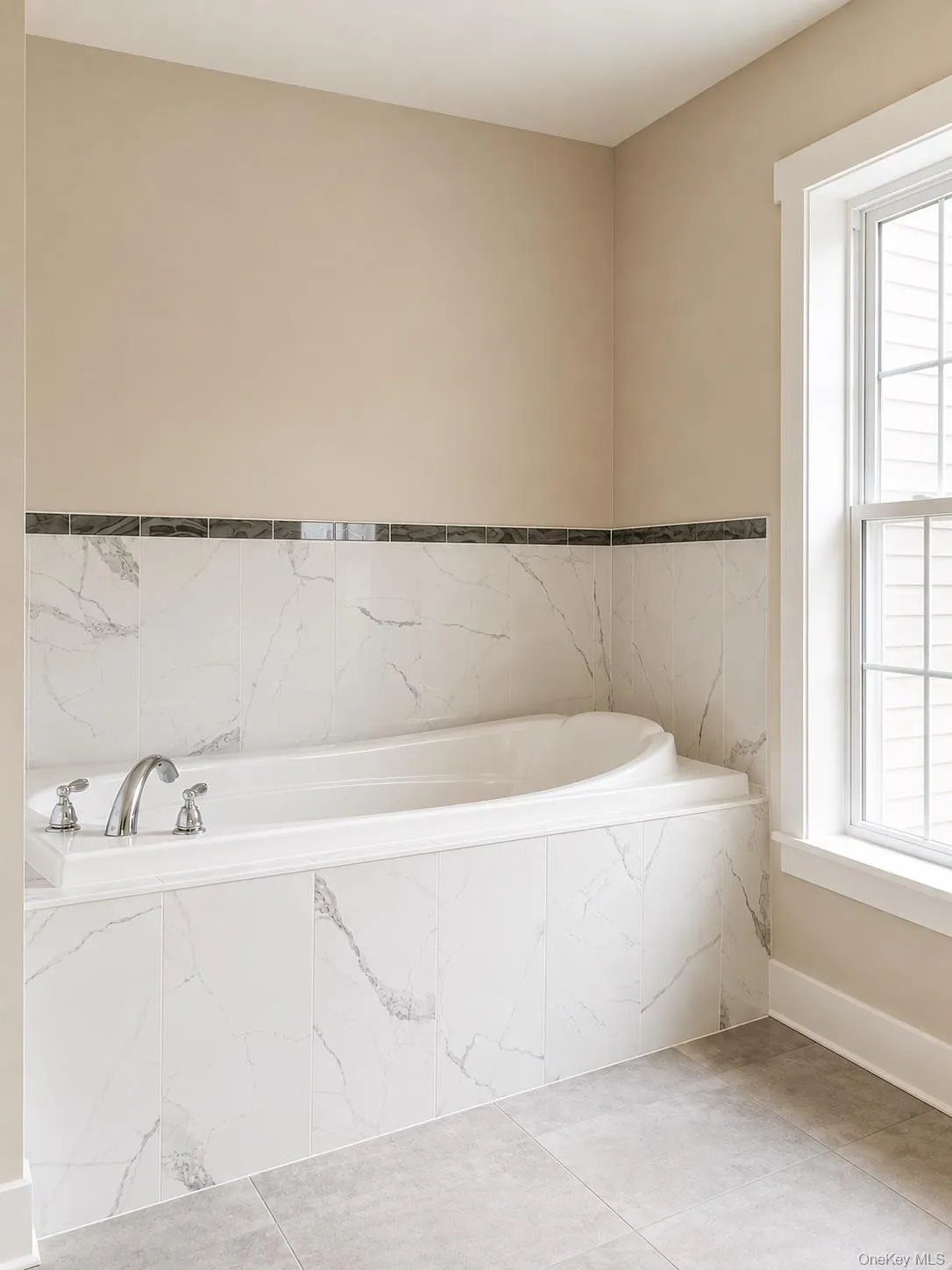 Soaking tub with chrome fixtures, surrounded by white marble-look tile Soaking tub with chrome fixtures, surrounded by white marble-look tile