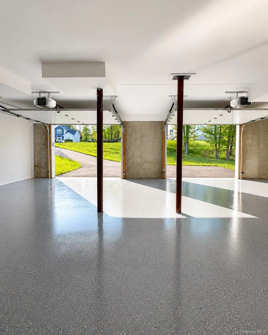 Expansive garage with a speckled epoxy floor finish and white painted walls Expansive garage with a speckled epoxy floor finish and white painted walls
