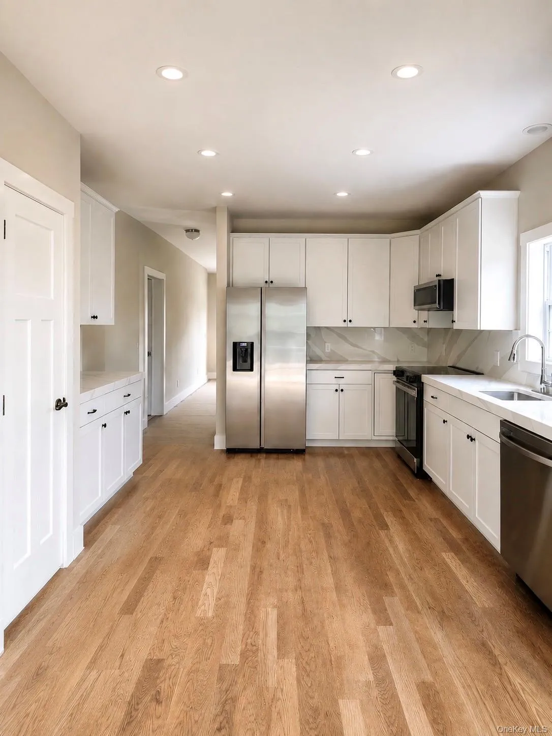 Open-concept kitchen featuring wood-finish flooring, white cabinetry, stainless steel appliances, white countertops, and recessed lighting Open-concept kitchen featuring wood-finish flooring, white cabinetry, stainless steel appliances, white countertops, and recessed lighting