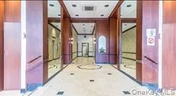 Lobby interior featuring wood paneling, recessed lighting, and a patterned tile floor with a central medallion detail Lobby interior featuring wood paneling, recessed lighting, and a patterned tile floor with a central medallion detail