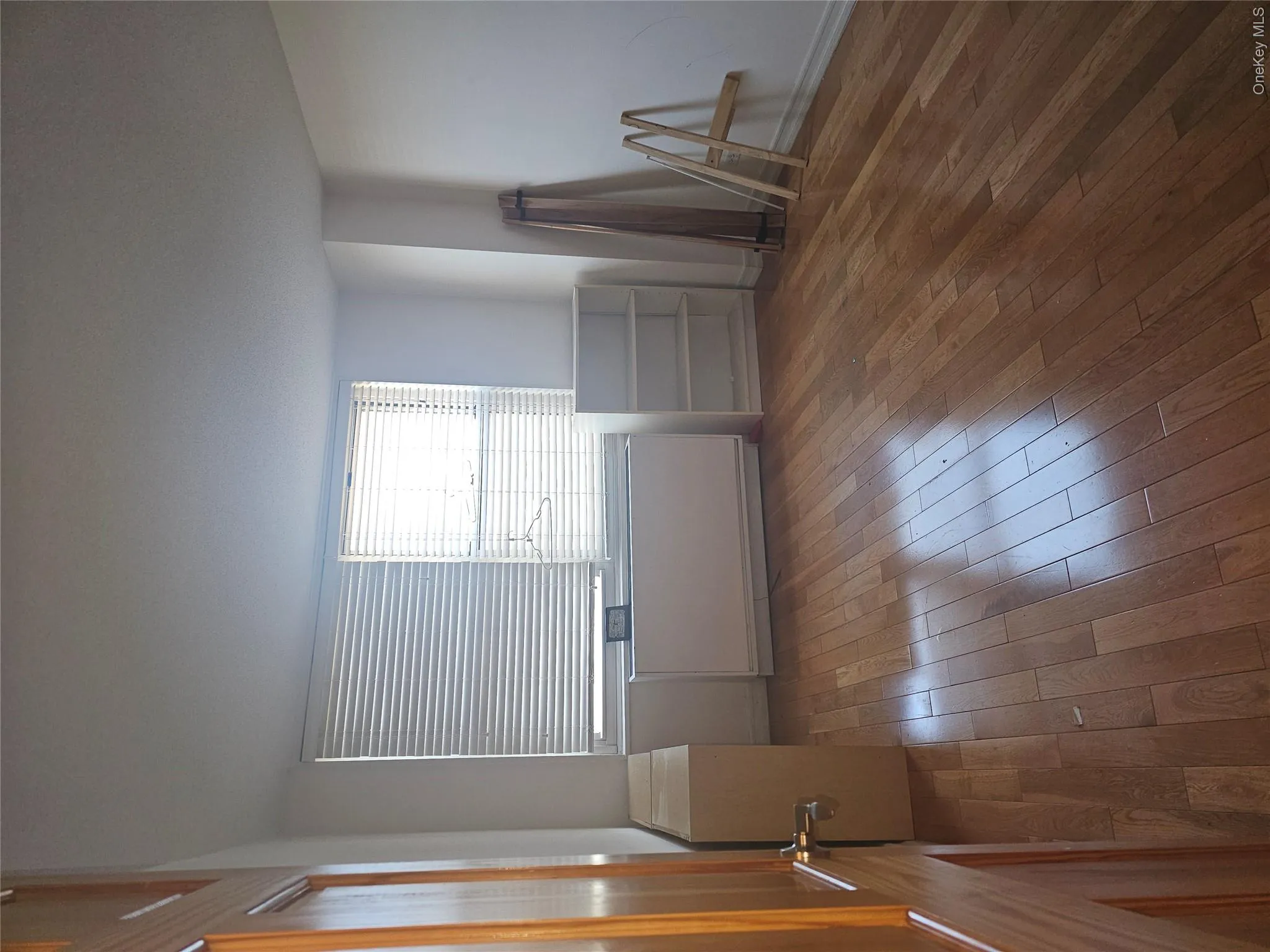 Bright interior space featuring wood-finish flooring, white walls, and two windows with horizontal blinds Bright interior space featuring wood-finish flooring, white walls, and two windows with horizontal blinds