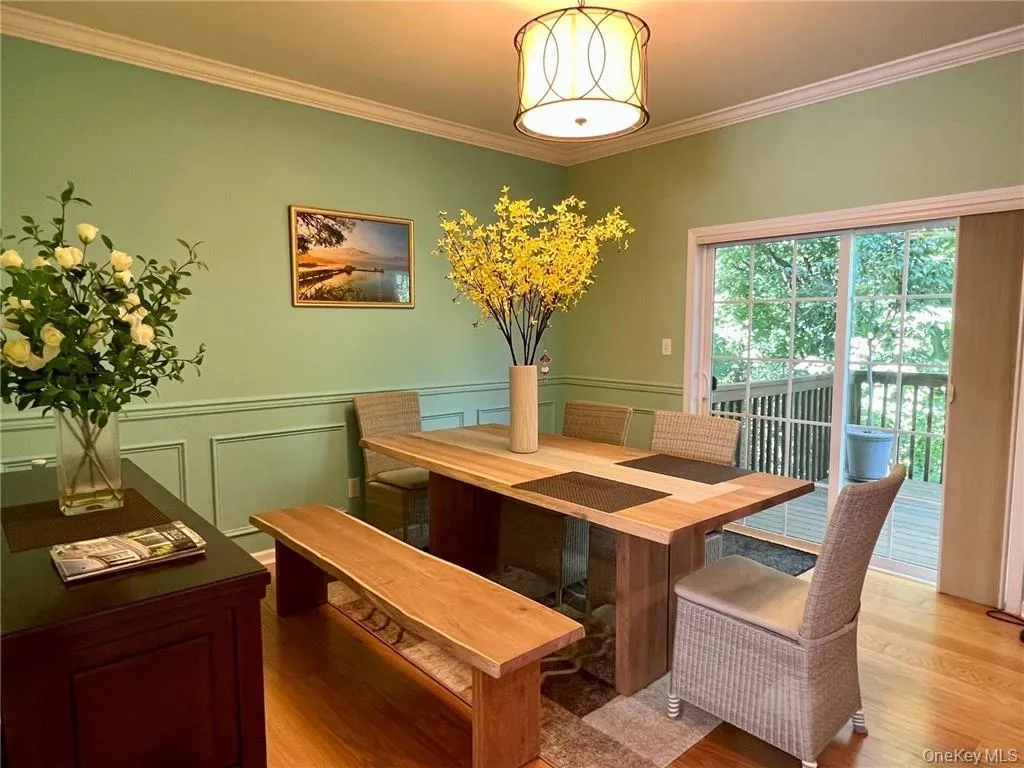 Dining room with ornamental molding, light wood-style flooring, and wainscoting Dining room with ornamental molding, light wood-style flooring, and wainscoting