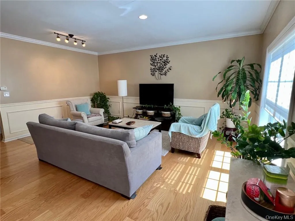 Living area with light wood-type flooring, ornamental molding, and wainscoting Living area with light wood-type flooring, ornamental molding, and wainscoting