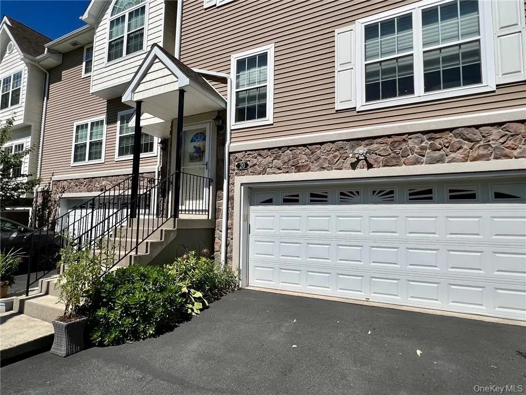 Entrance to property with stone siding, a garage, and asphalt driveway Entrance to property with stone siding, a garage, and asphalt driveway