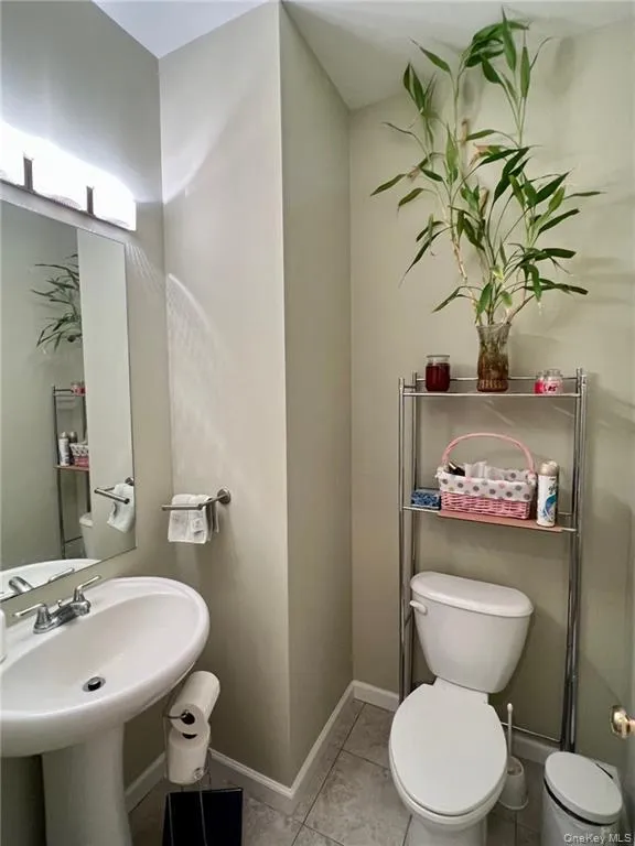 Bathroom featuring toilet, tile patterned floors, a sink, and baseboards Bathroom featuring toilet, tile patterned floors, a sink, and baseboards