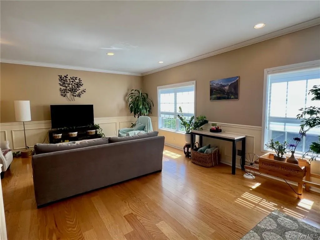 Living area with light wood-type flooring, crown molding, a wainscoted wall, and a decorative wall Living area with light wood-type flooring, crown molding, a wainscoted wall, and a decorative wall