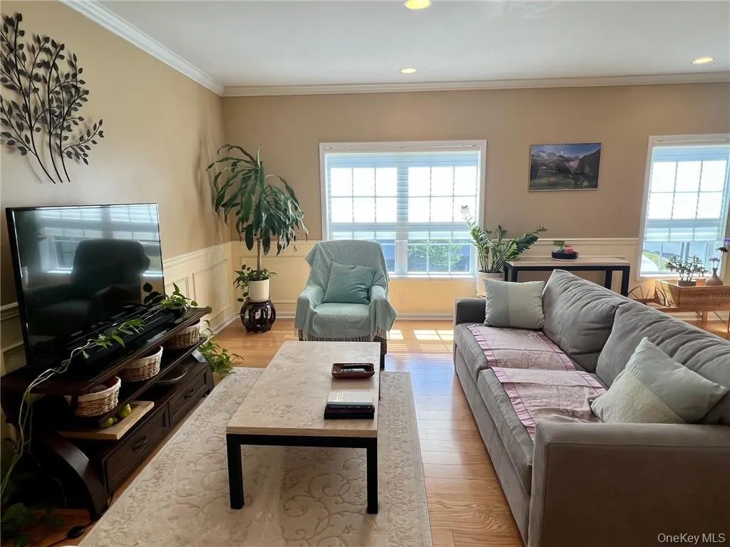 Living room featuring crown molding, a wainscoted wall, recessed lighting, and light wood-style floors Living room featuring crown molding, a wainscoted wall, recessed lighting, and light wood-style floors