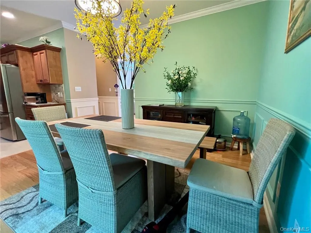 Dining room with ornamental molding, a chandelier, a wainscoted wall, a decorative wall, and light wood-style floors Dining room with ornamental molding, a chandelier, a wainscoted wall, a decorative wall, and light wood-style floors