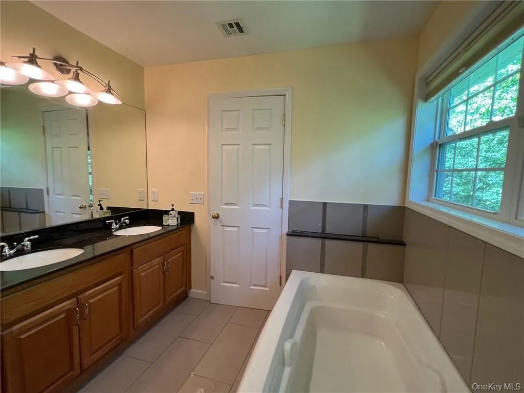 Bathroom featuring a tub, tile patterned flooring, and double vanity Bathroom featuring a tub, tile patterned flooring, and double vanity