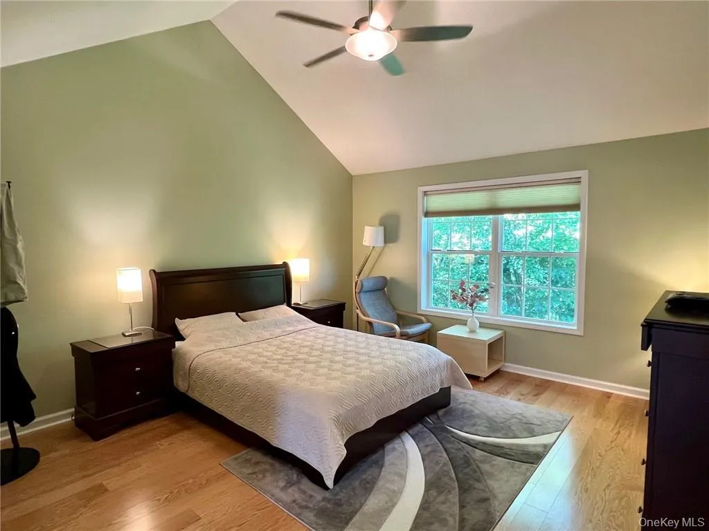 Bedroom with light wood-type flooring, vaulted ceiling, baseboards, and a ceiling fan Bedroom with light wood-type flooring, vaulted ceiling, baseboards, and a ceiling fan