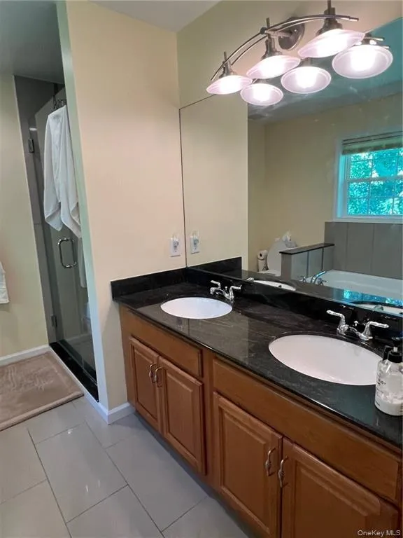 Full bathroom with a shower stall, tile patterned flooring, double vanity, and a tub to relax in Full bathroom with a shower stall, tile patterned flooring, double vanity, and a tub to relax in