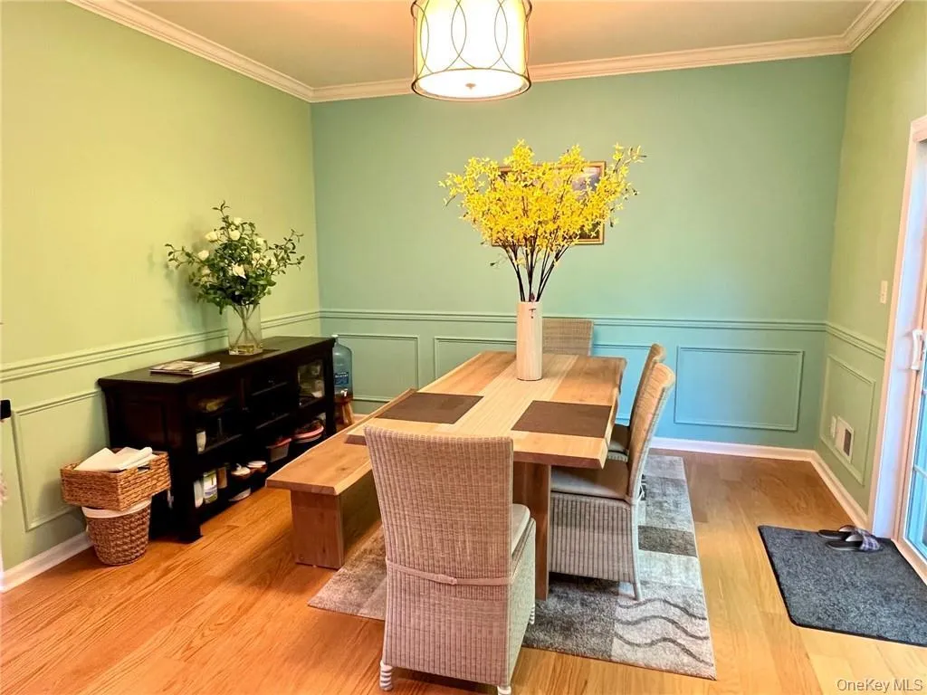 Dining area with a decorative wall, wood finished floors, ornamental molding, and wainscoting Dining area with a decorative wall, wood finished floors, ornamental molding, and wainscoting