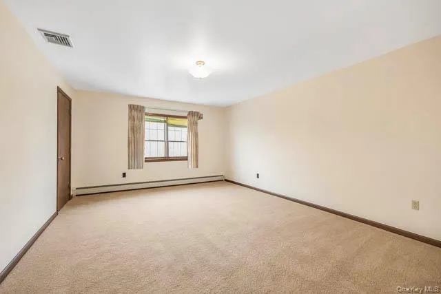 Spacious room featuring neutral carpeting, light-toned walls, and a ceiling-mounted light fixture Spacious room featuring neutral carpeting, light-toned walls, and a ceiling-mounted light fixture