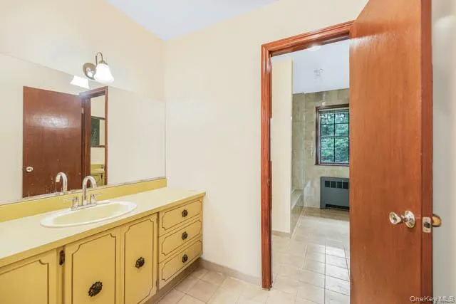 Bathroom vanity with an integrated sink, dual-handle faucet, and overhead wall sconce lighting Bathroom vanity with an integrated sink, dual-handle faucet, and overhead wall sconce lighting