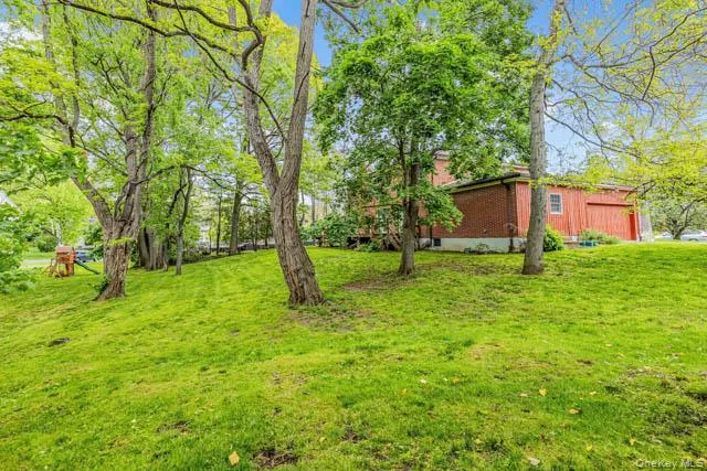 Expansive green lawn with mature trees and a brick-sided structure Expansive green lawn with mature trees and a brick-sided structure