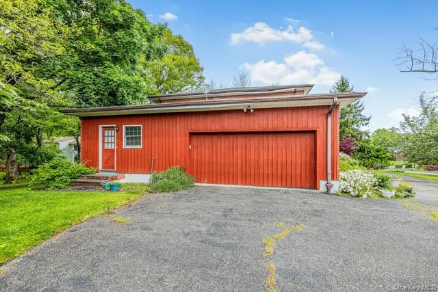 Red-toned vertical siding with a prominent garage door and a separate entry door Red-toned vertical siding with a prominent garage door and a separate entry door