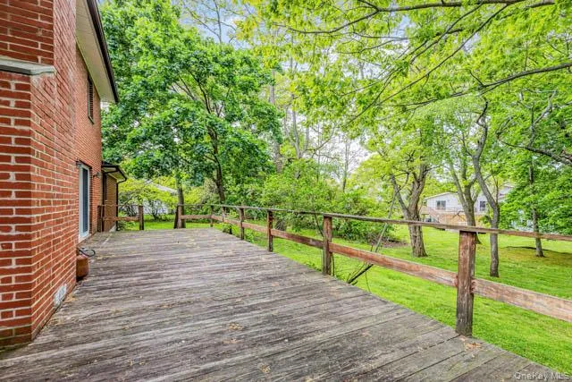 Spacious wood deck with a natural wood railing, set against a red brick exterior Spacious wood deck with a natural wood railing, set against a red brick exterior