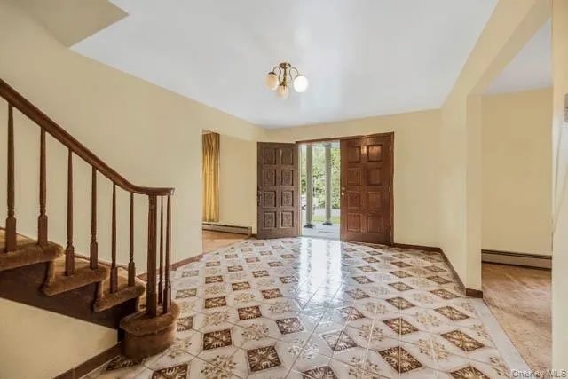 Foyer featuring patterned tile flooring, a wood staircase with carpeted treads, and double entry doors Foyer featuring patterned tile flooring, a wood staircase with carpeted treads, and double entry doors