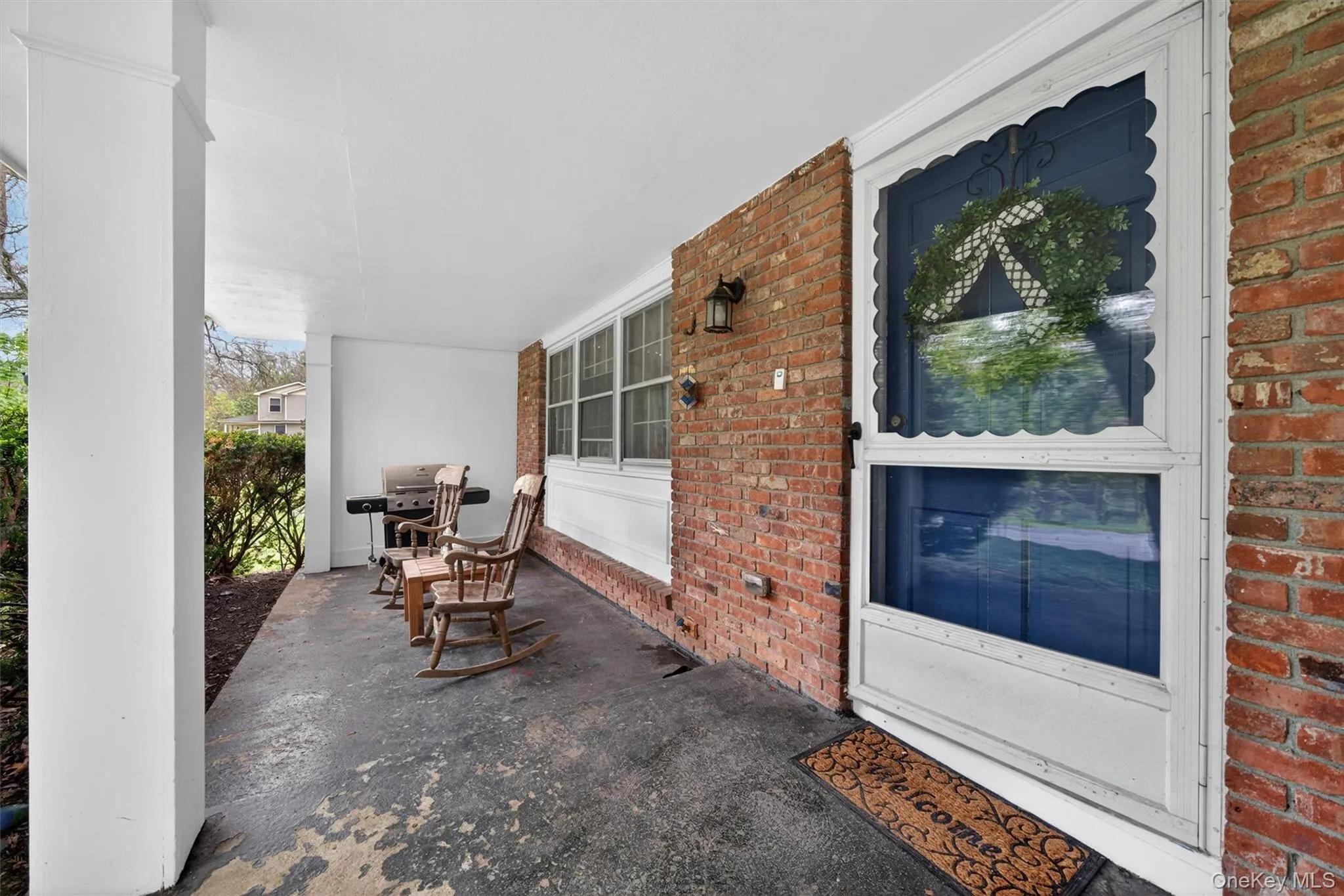 Covered porch featuring a brick facade, white support columns, and a concrete floor Covered porch featuring a brick facade, white support columns, and a concrete floor