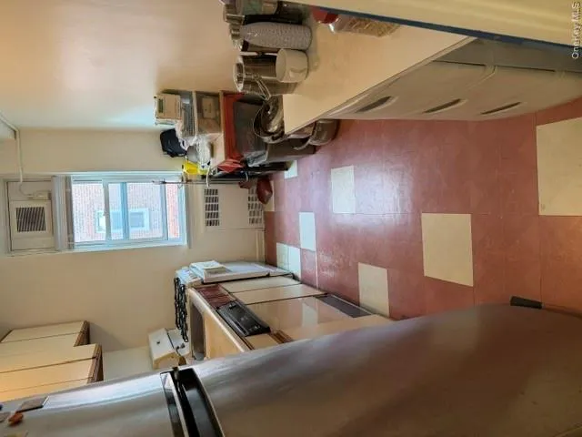 Galley kitchen featuring a window, checkerboard tile flooring, built-in upper cabinetry, and a window-mounted air conditioning unit Galley kitchen featuring a window, checkerboard tile flooring, built-in upper cabinetry, and a window-mounted air conditioning unit