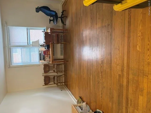 Hardwood flooring throughout the room, complemented by a large window with horizontal blinds Hardwood flooring throughout the room, complemented by a large window with horizontal blinds