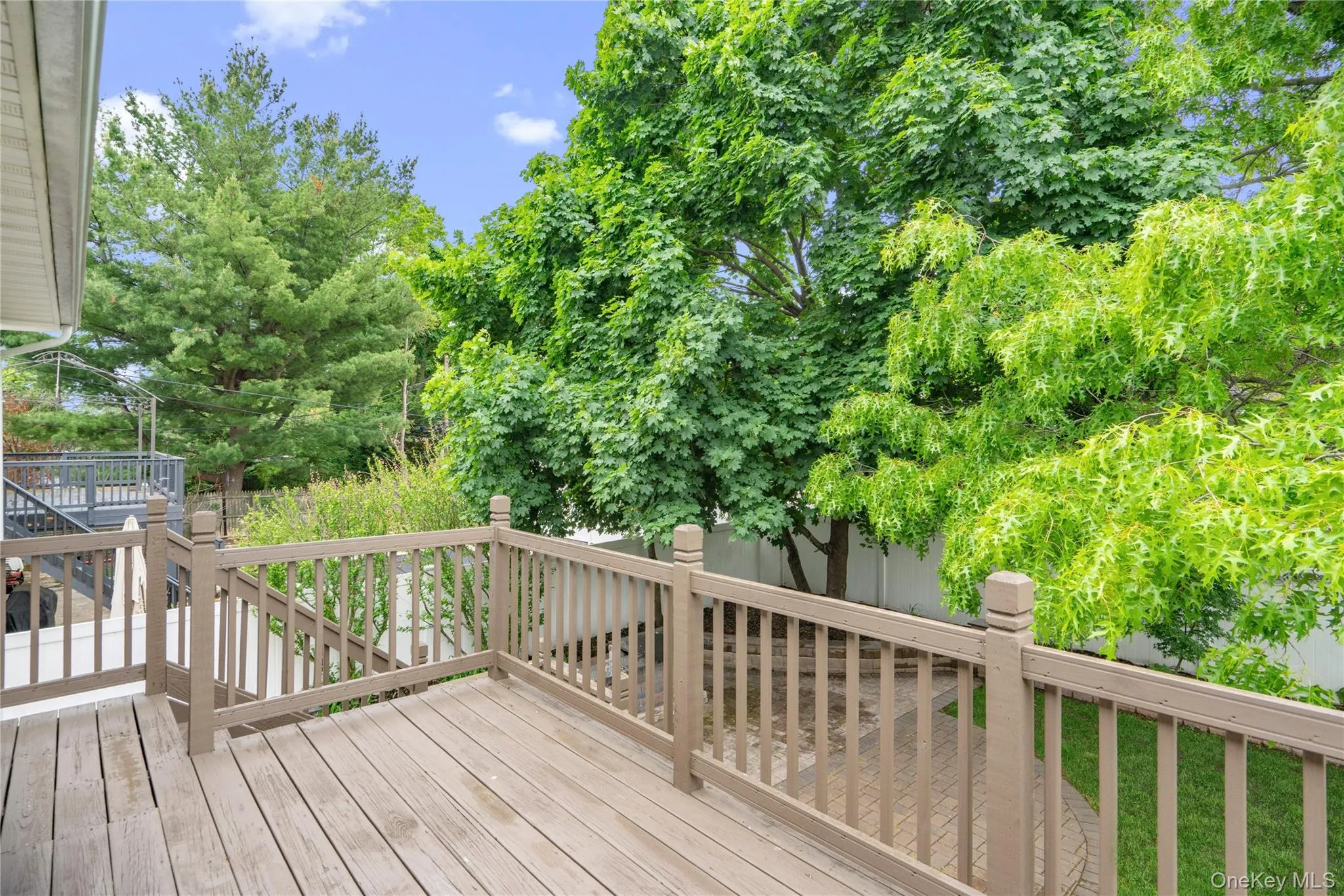 Expansive outdoor deck with wood-finish flooring and full railing system Expansive outdoor deck with wood-finish flooring and full railing system