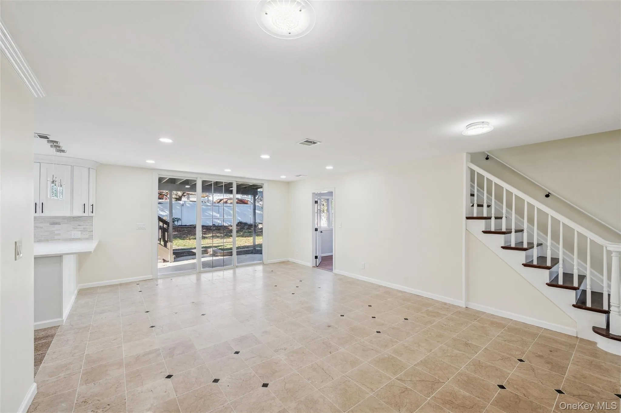 Expansive open-concept room featuring neutral wall tones, large format tile flooring with contrasting accent tiles, and recessed lighting Expansive open-concept room featuring neutral wall tones, large format tile flooring with contrasting accent tiles, and recessed lighting