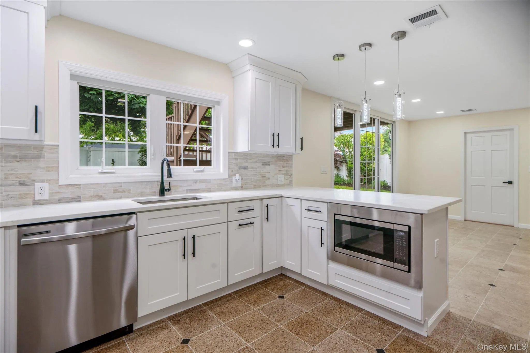 Modern kitchen featuring white cabinetry, stainless steel appliances, a white countertop, and a tiled backsplash Modern kitchen featuring white cabinetry, stainless steel appliances, a white countertop, and a tiled backsplash