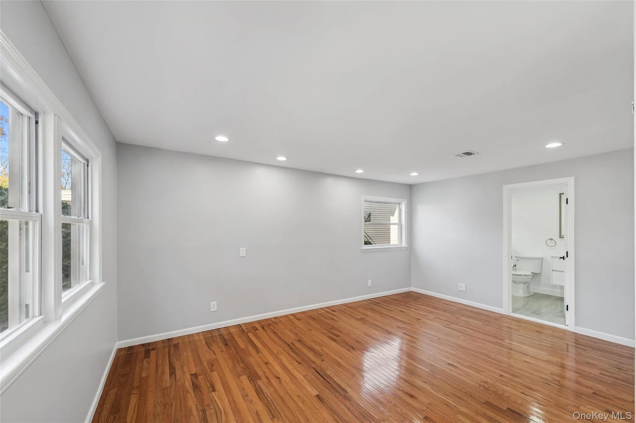 First Floor Primary Bedroom with wood-finish flooring, recessed lighting, and en-suite First Floor Primary Bedroom with wood-finish flooring, recessed lighting, and en-suite