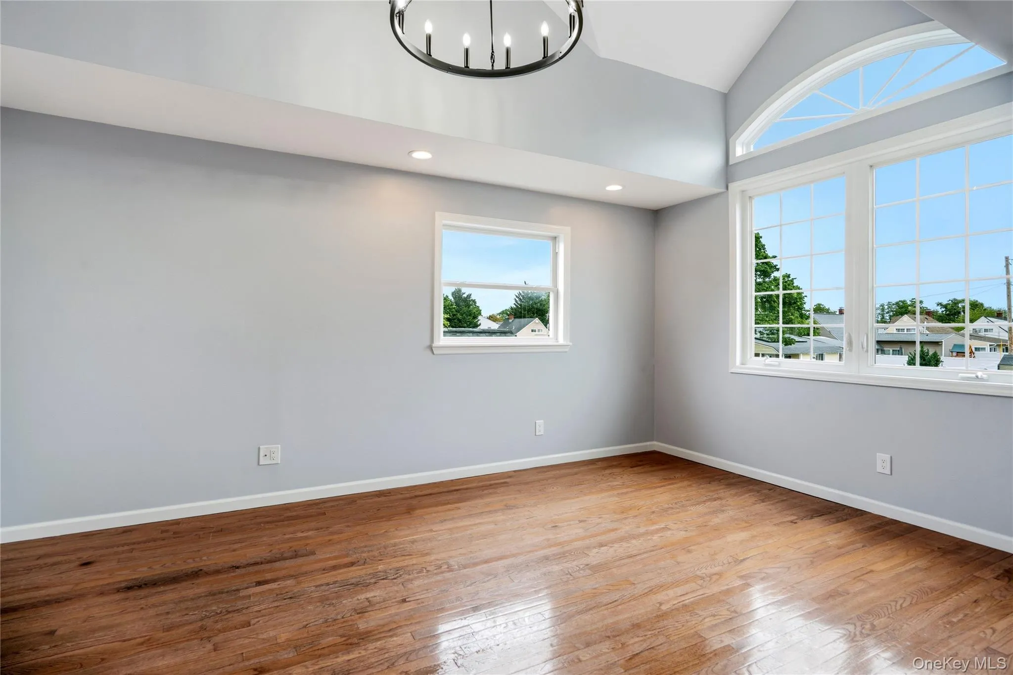 Bedroom featuring vaulted ceilings with an arched window, hardwood flooring, and recessed lighting Bedroom featuring vaulted ceilings with an arched window, hardwood flooring, and recessed lighting