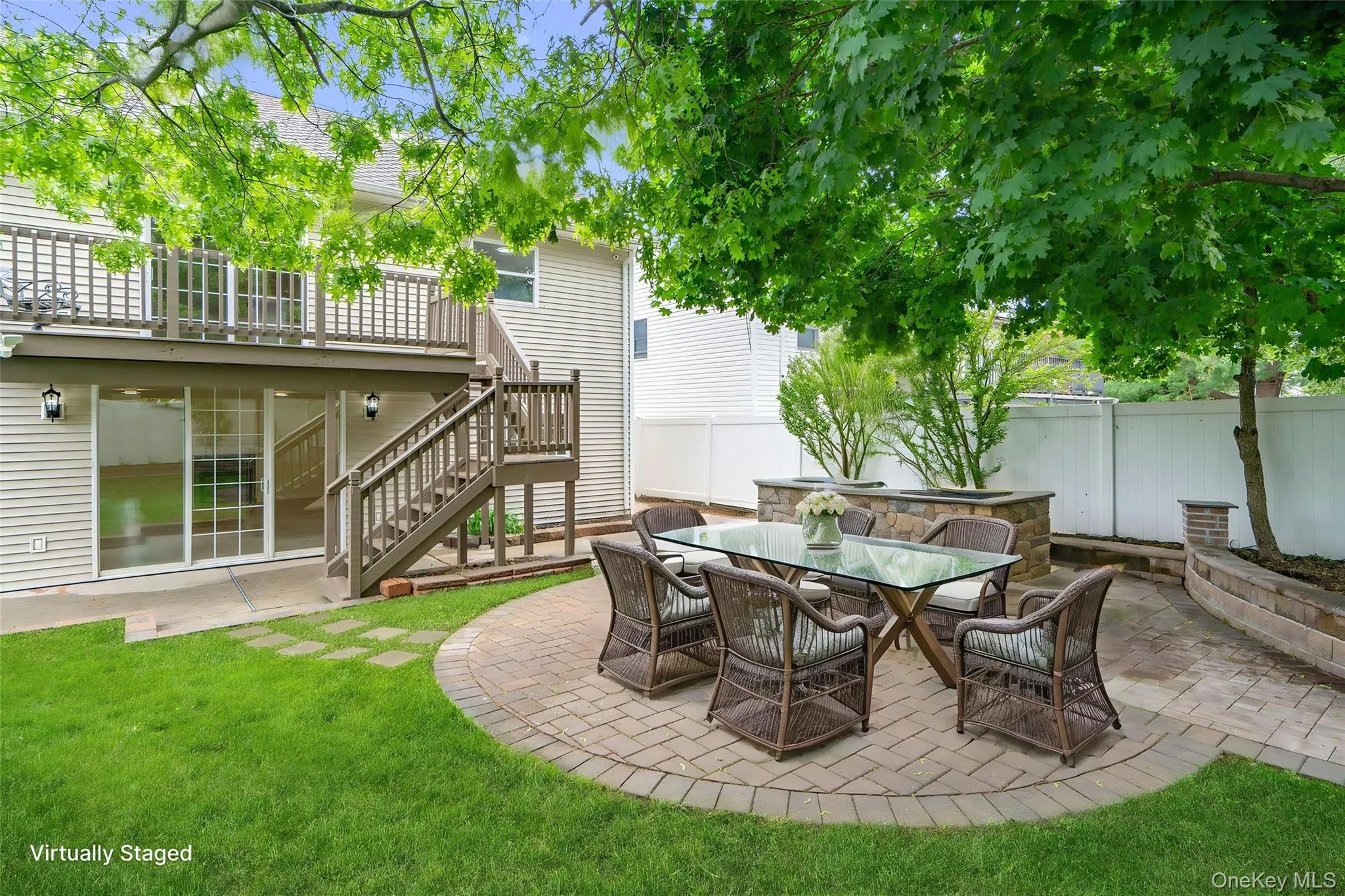 Expansive backyard featuring a circular paver patio, stone-faced raised planters, and a manicured lawn Expansive backyard featuring a circular paver patio, stone-faced raised planters, and a manicured lawn