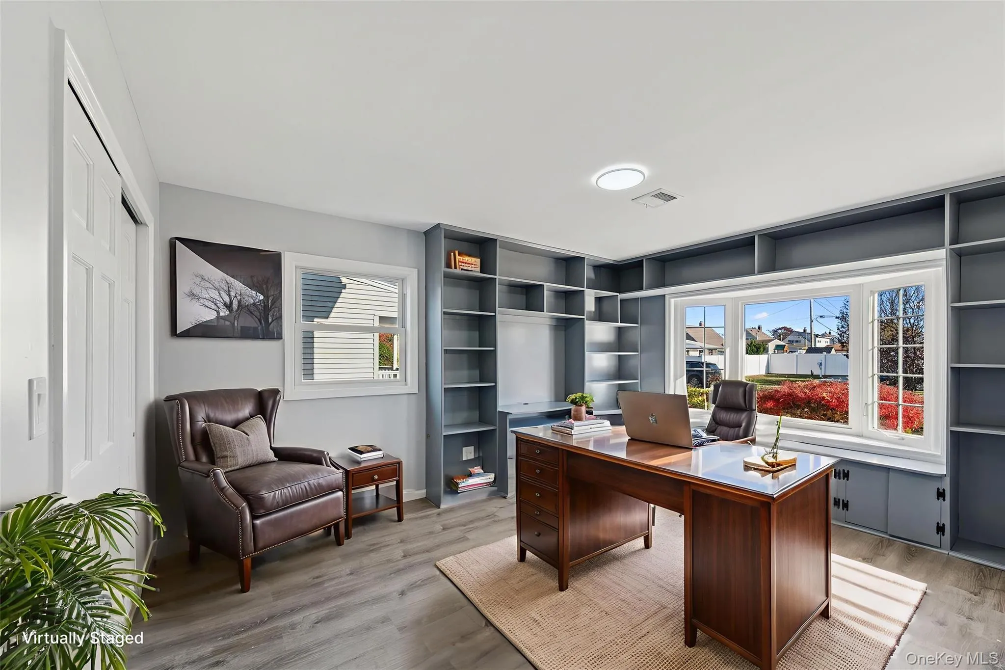 Dedicated room featuring extensive built-in shelving, a prominent bay window, recessed lighting, and wood-finish flooring Dedicated room featuring extensive built-in shelving, a prominent bay window, recessed lighting, and wood-finish flooring