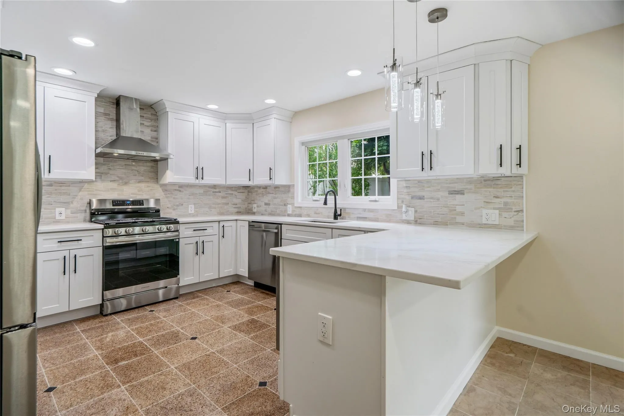 Modern kitchen featuring white shaker cabinetry, stainless steel appliances, light-toned tiled backsplash, and recessed lighting Modern kitchen featuring white shaker cabinetry, stainless steel appliances, light-toned tiled backsplash, and recessed lighting