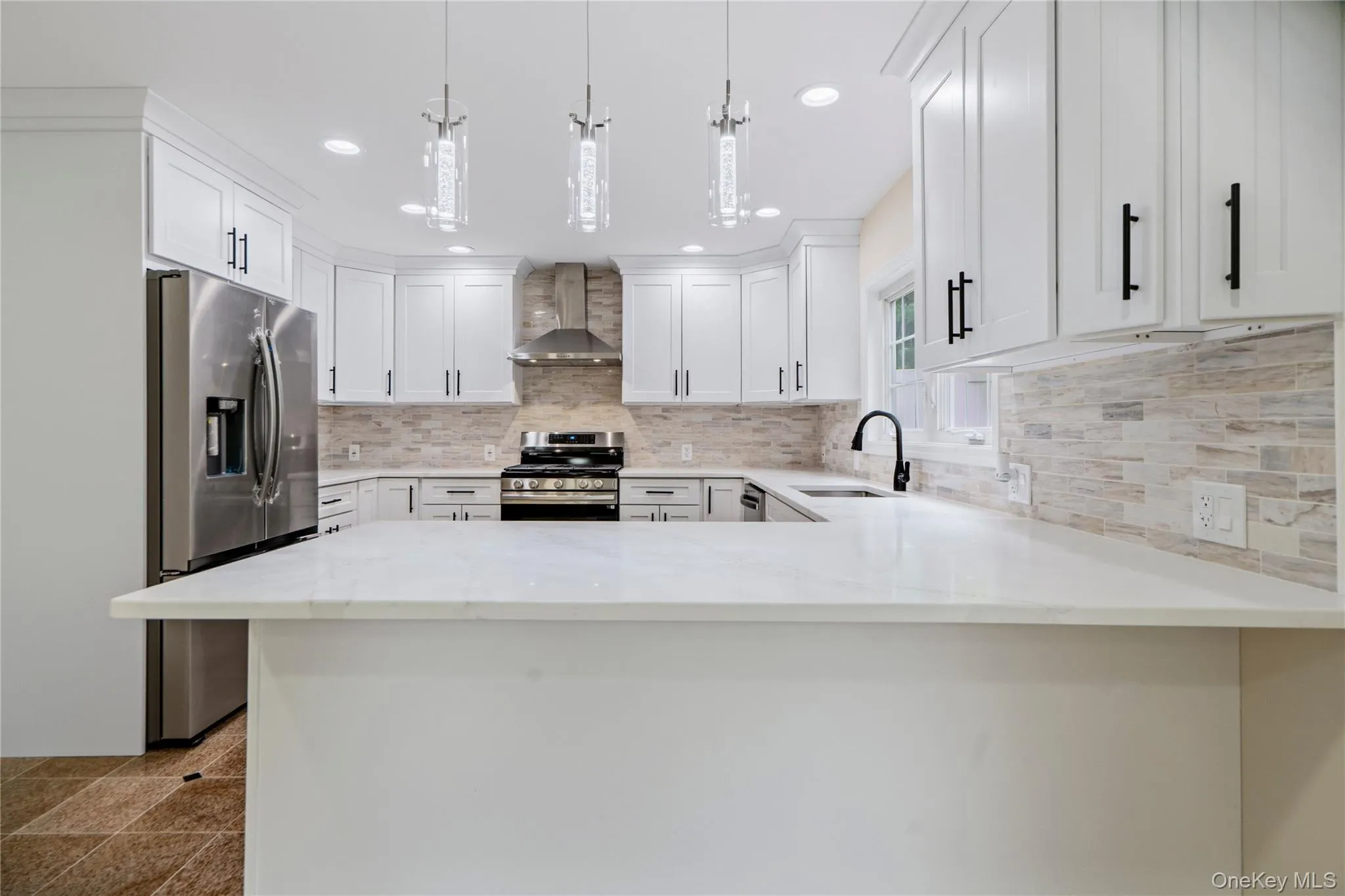 White kitchen featuring a U-shaped layout, quartz countertops, and a full tile backsplash White kitchen featuring a U-shaped layout, quartz countertops, and a full tile backsplash