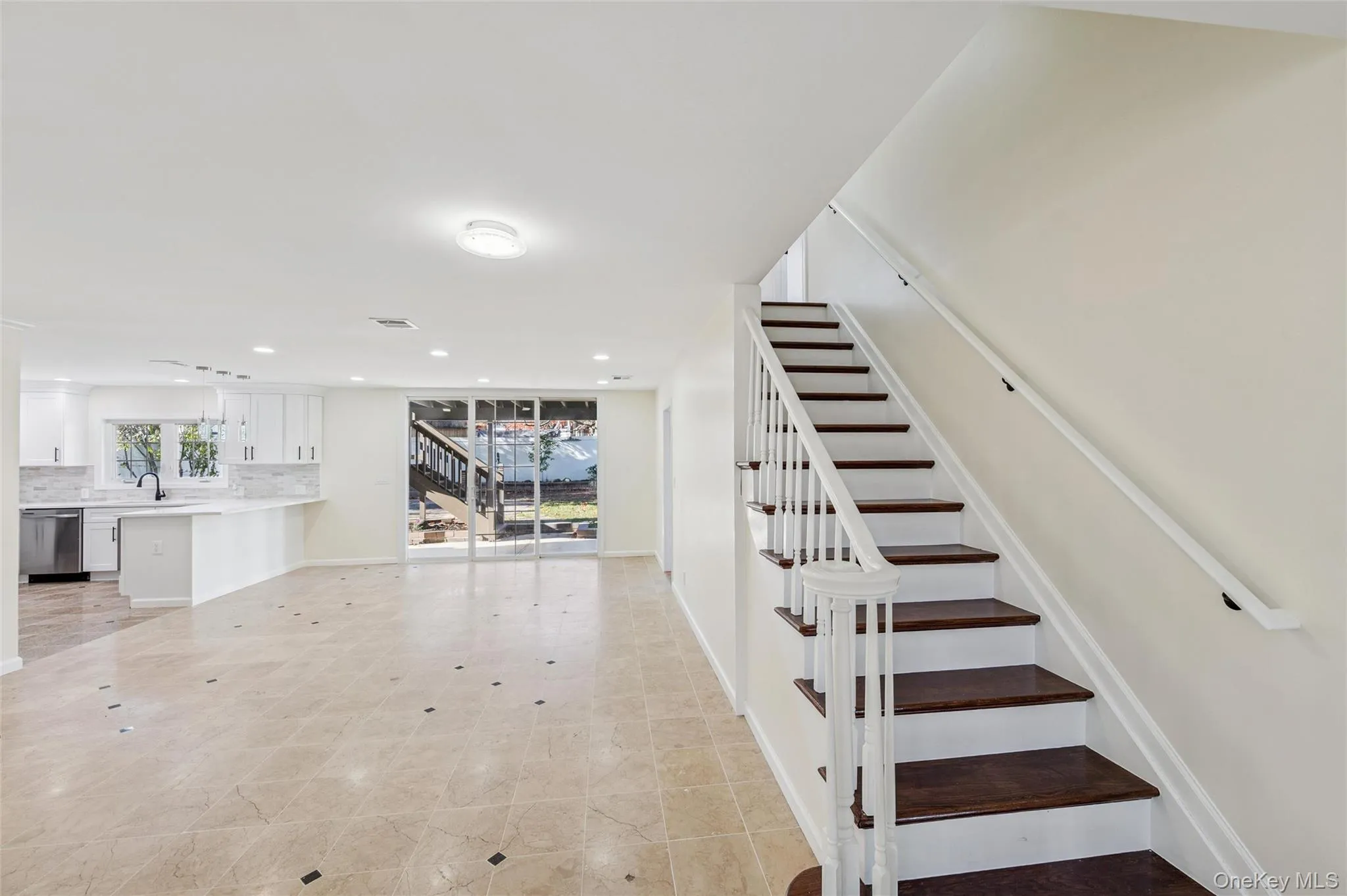 Tiled flooring with dark accent inlays, a white staircase with dark wood-finish treads, and recessed lighting Tiled flooring with dark accent inlays, a white staircase with dark wood-finish treads, and recessed lighting