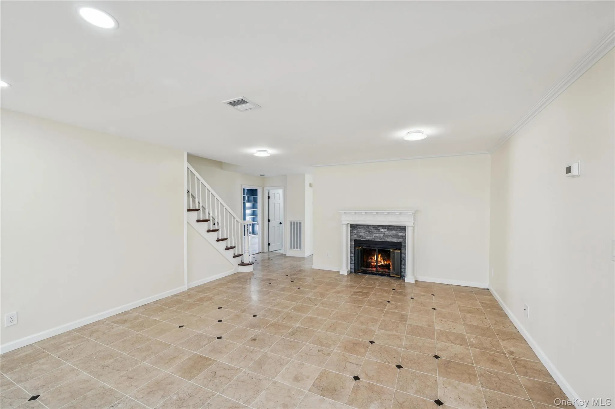Living area featuring a fireplace with a stone surround and white mantel, recessed lighting, crown molding, and diagonal tile flooring with accent squares Living area featuring a fireplace with a stone surround and white mantel, recessed lighting, crown molding, and diagonal tile flooring with accent squares